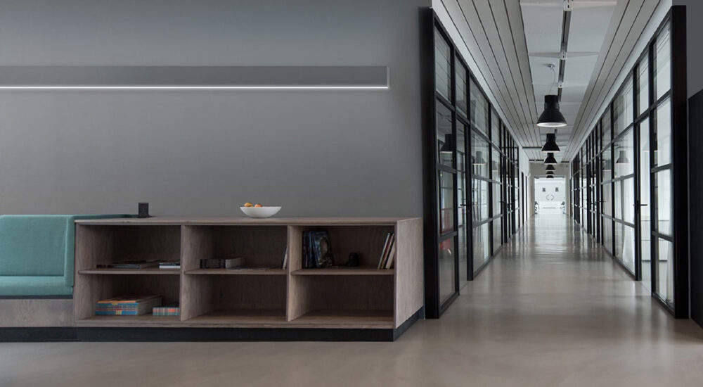 A wall-mounted linear LED fixture washes a wall with light