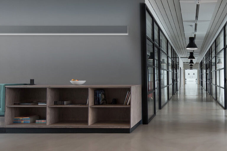 A wall-mounted linear LED fixture washes a wall with light